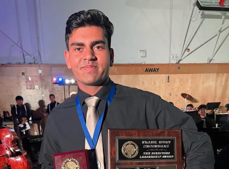 Holding a Directors Leadership Award plaque and a medal at the Frank Hurt Secondary band concert