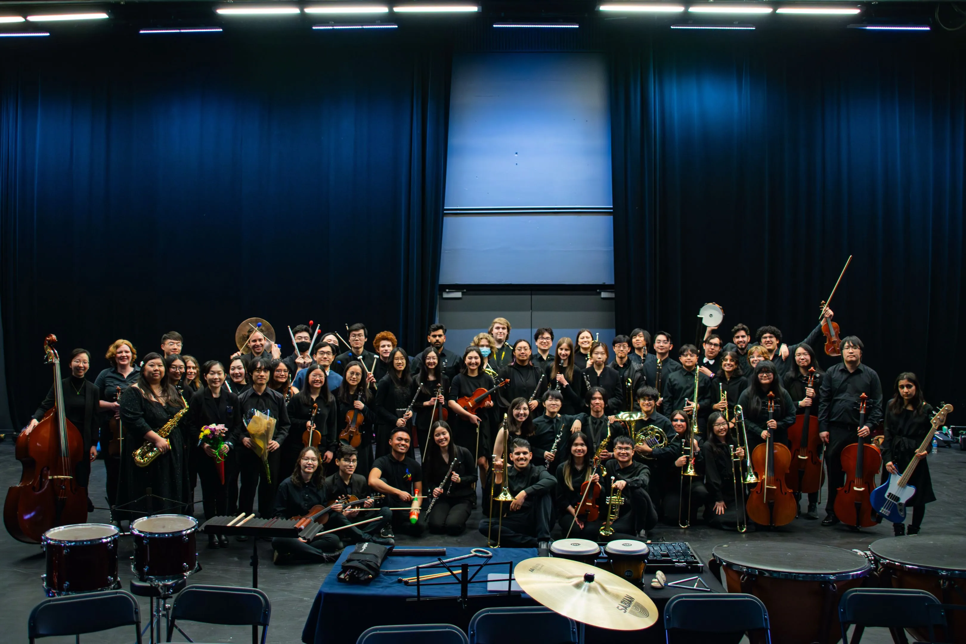 The SFU Concert Orchestra posing together on stage with their instruments